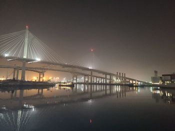 Illuminated bridge over river against sky at night