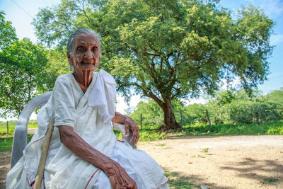 Portrait of wrinkled senior woman sitting on chair at farm