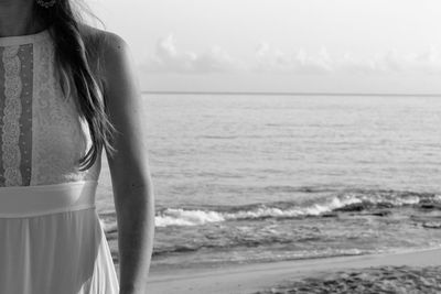 Young woman standing by sea against sky