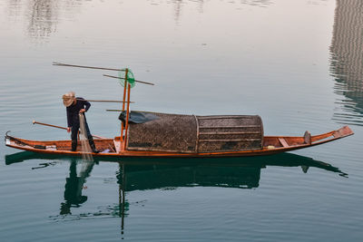 Reflection of man on boat in lake
