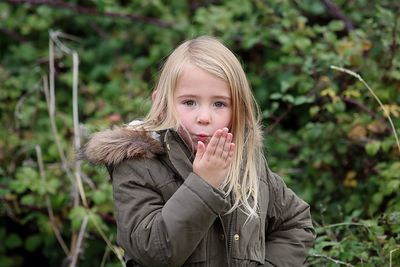 Portrait of girl standing against plant