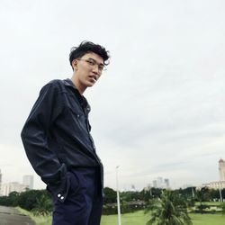 Young man standing against sky