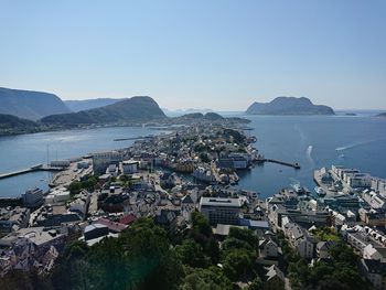 Cityscape by sea against clear blue sky