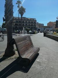 Park bench by building against sky