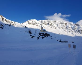 Scenic view of snow covered mountains against blue sky