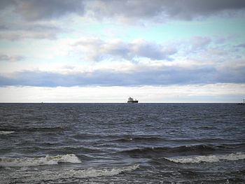 Boats in sea against cloudy sky