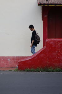 Side view of young man standing against wall