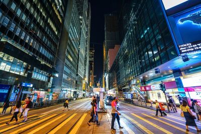 People on city street amidst buildings at night