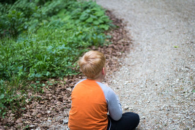 Rear view of boy sitting outdoors