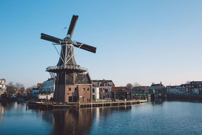 Traditional windmill by river in city