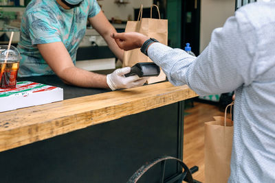 Midsection of couple holding hands while sitting on table