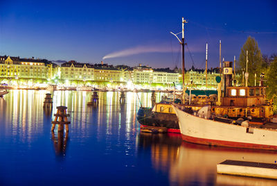 Sailboats moored at illuminated harbor against sky