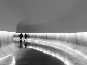 Rear view of silhouette walking in illuminated tunnel