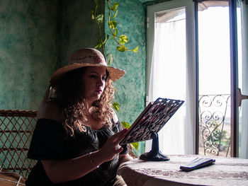 Woman reading book on table at home