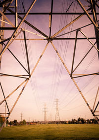 Low angle view of electricity pylon on field against sky