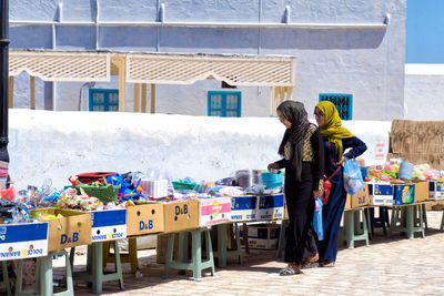 Rear view of woman standing on table against buildings in city