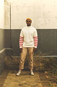 Full length of young man standing against wall