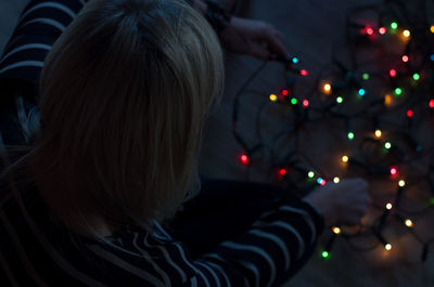 Rear view of woman with illuminated christmas lights at night