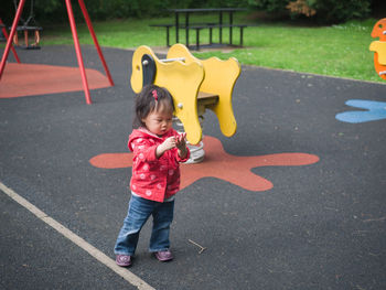 Full length of girl standing by spring ride at playground