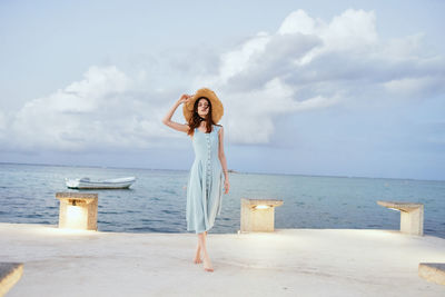 Woman standing at beach against sky