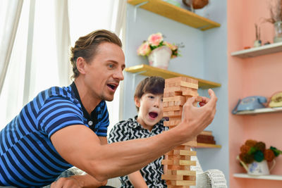 Father and son stacking dominoes at home