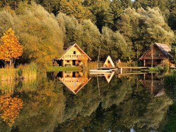 Houses by lake in forest during autumn