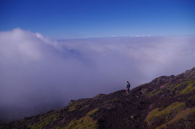 Rear view of man standing on mountain against sky