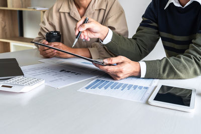 Midsection of business people working on table