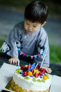 Baby boy with birthday cake on table