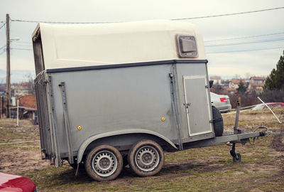Grey horse transportation van with muddy tires parked outside of the ranch during the day