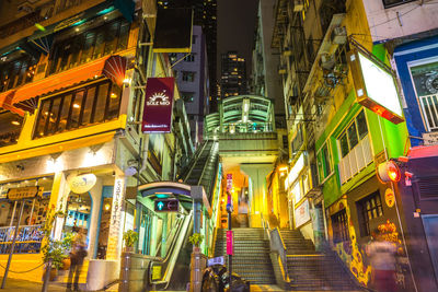 Illuminated street amidst buildings in city at night