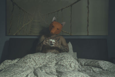 Young man sitting on bed at home