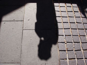 Low section of woman shadow on tiled floor