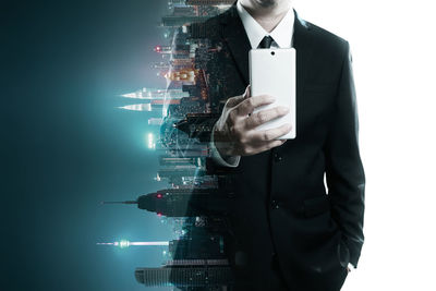 Digital composite image of man using mobile phone and illuminated buildings