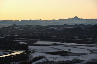 Scenic view of agricultural landscape against clear sky during sunset