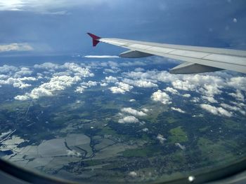 Aerial view of airplane wing over landscape against sky