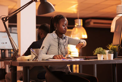 Portrait of young woman using mobile phone while sitting at cafe