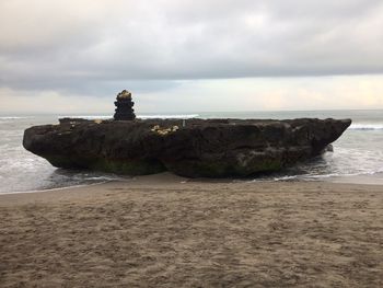 Rock formation on beach against sky