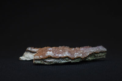 Close-up of bread on table against black background