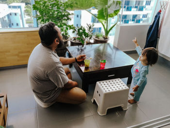 Father and daughter on floor by table at home