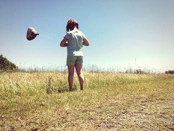 Full length rear view of young woman standing on field