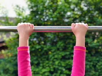 Cropped hands of girl holding horizontal bar while playing at playground