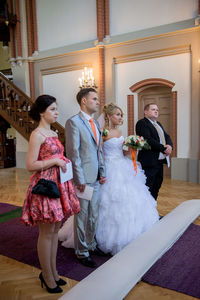 Young couple standing with bridesmaid and groomsman in church