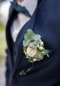 Midsection of groom wearing suit with boutonniere 