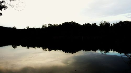 Silhouette trees by lake against sky during sunset