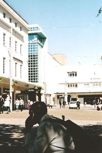 People sitting in front of buildings against clear sky