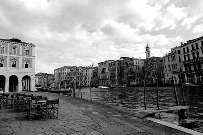 Empty chairs by street against buildings in city