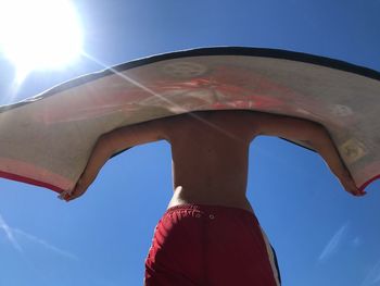 Low angle view of person against blue sky on sunny day