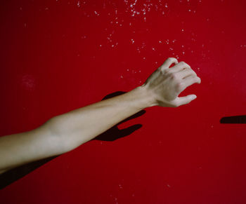 Cropped image of hand on red table against gray background