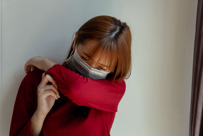 Woman holding red while standing against wall at home